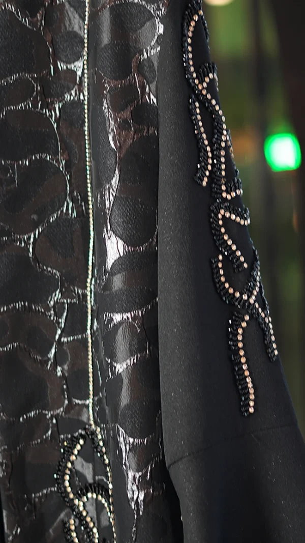 مانتو عبایی مشکی با پارچه براق طرحدار، سنگ‌دوزی دستی روی آستین و جلو، مناسب سایز ۳۸ تا ۵۰